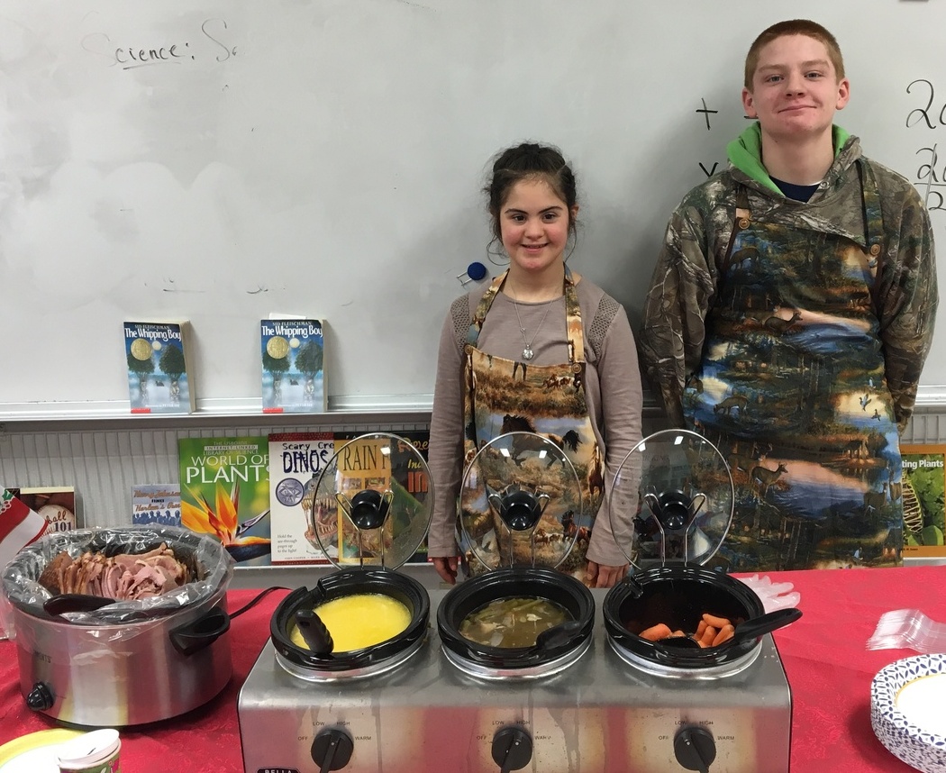 boy and girl wearing aprons in front of crockpots